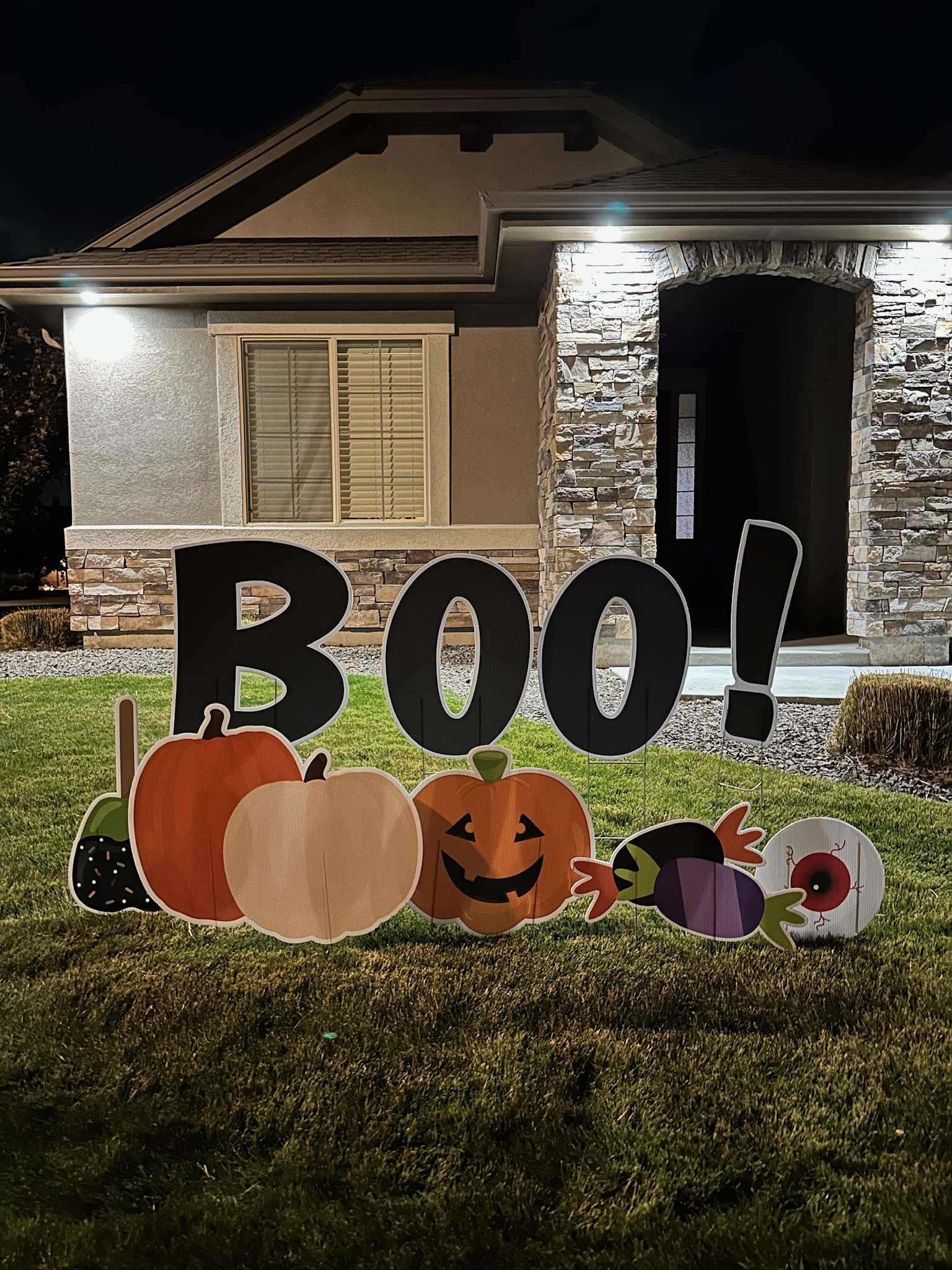 Halloween BOO yard card display lit up at night with glowing letters and spooky art in a Boise yard