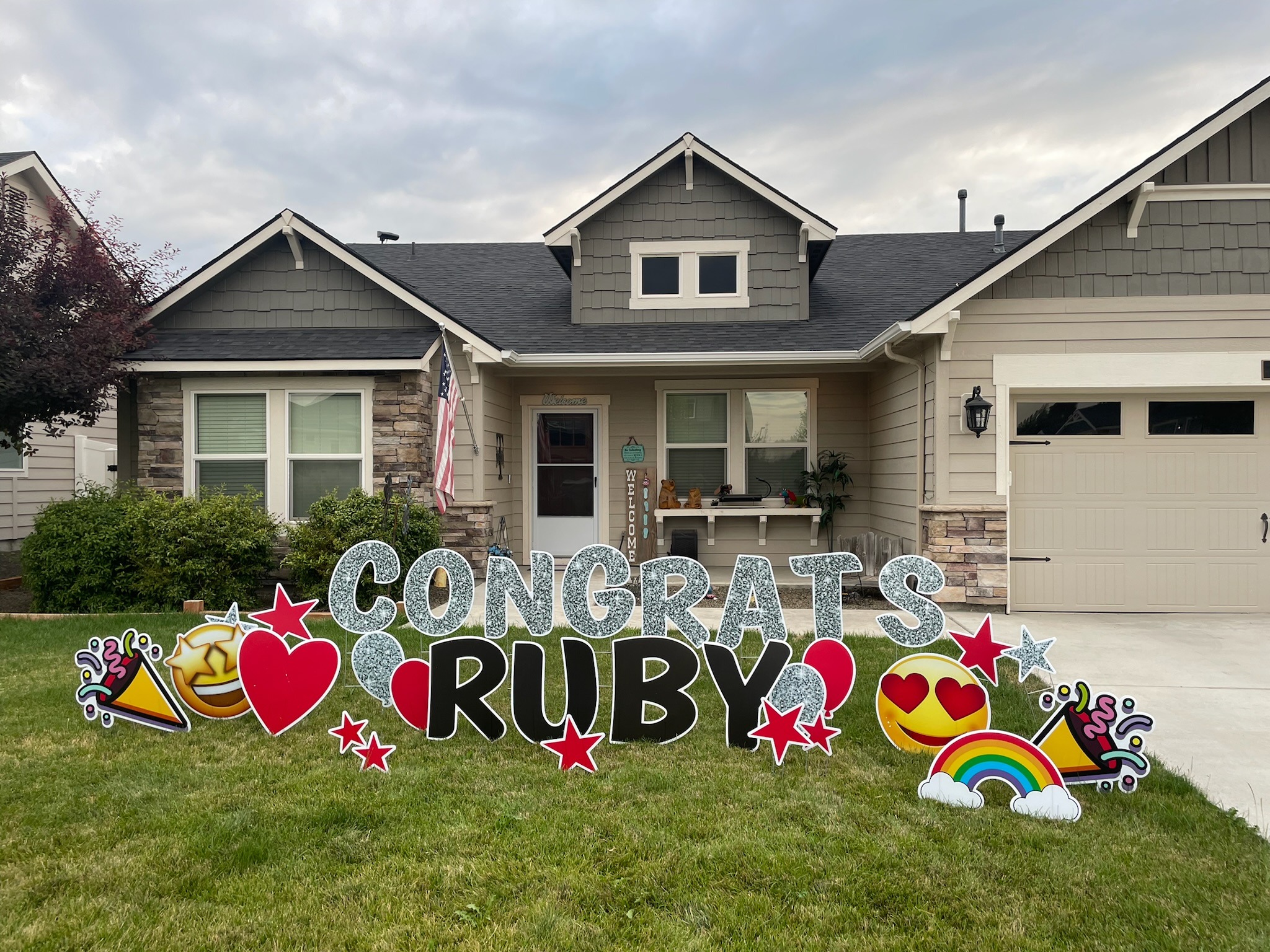 Congrats Ruby graduation yard card display with glitter letters emoji and rainbow art in Boise Idaho